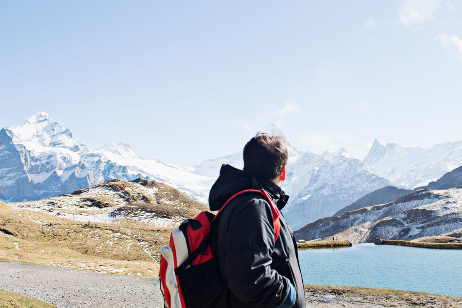 A hiker with a backpack exploring the stunning snowy landscapes of the Swiss Alps near Grindelwald.