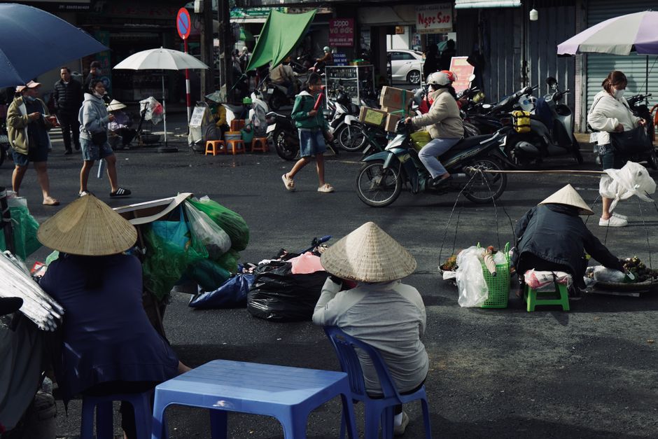 Vibrant Vietnamese street market bustling with activity and locals in traditional hats.